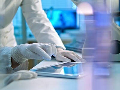 Two scientists in a high-tech biology lab examine a tablet computer.