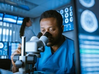 A scientist looks into the eyepiece of a microscope in a research laboratory.